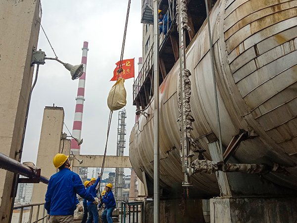 5月10日中午，在動力車間三期工藝除氧器地面，黨員突擊隊隊員用滑輪往工藝除氧器平臺運送鋼絲網(wǎng)，用以纏繞新填料.jpg